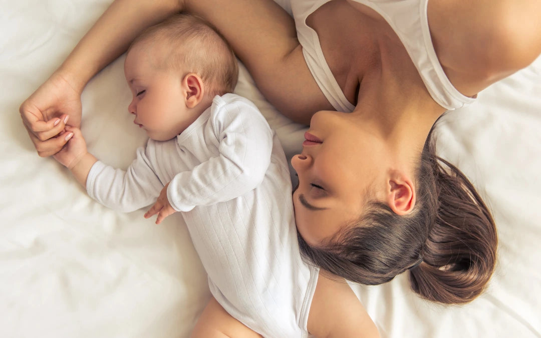 Un bébé et sa maman couché sur un lit blanc