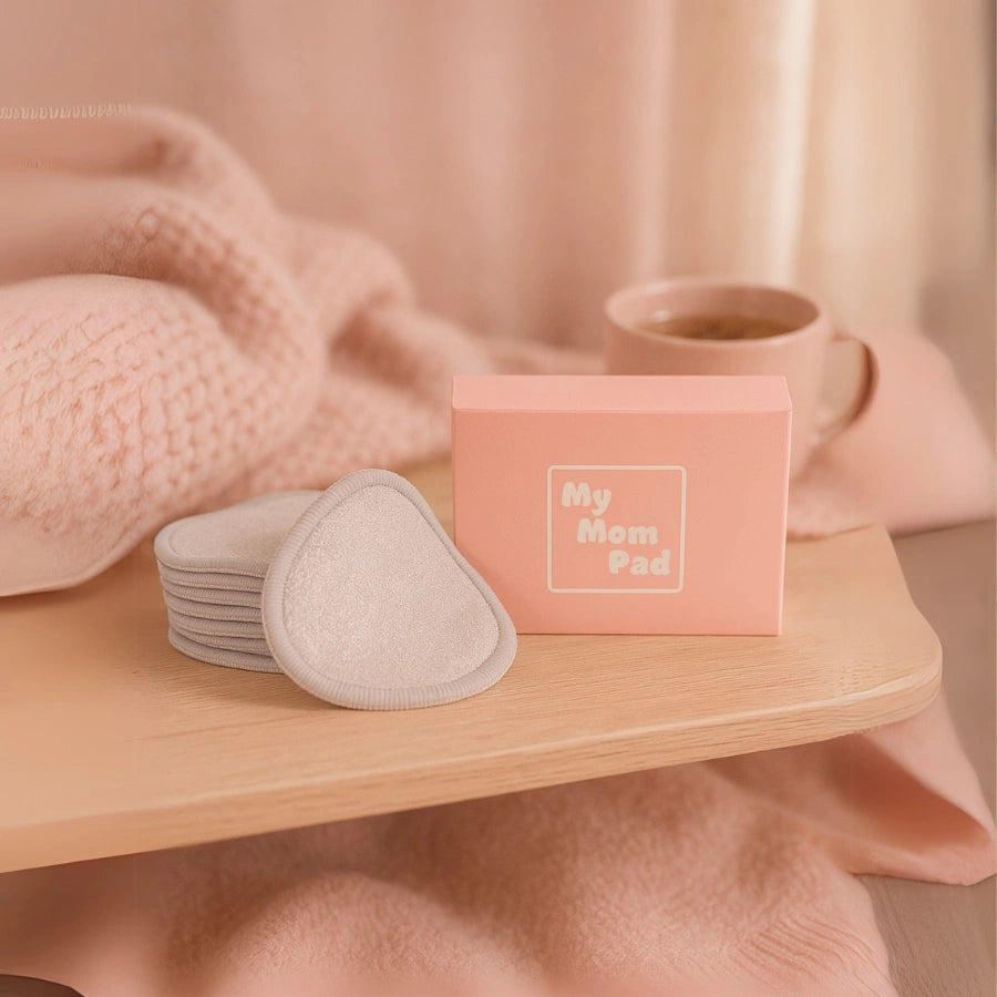 Coussinets d’allaitement lavables beiges avec boîte de rangement "My Mom Pad", posés sur une table en bois. Une solution douce et réutilisable pour l’allaitement.