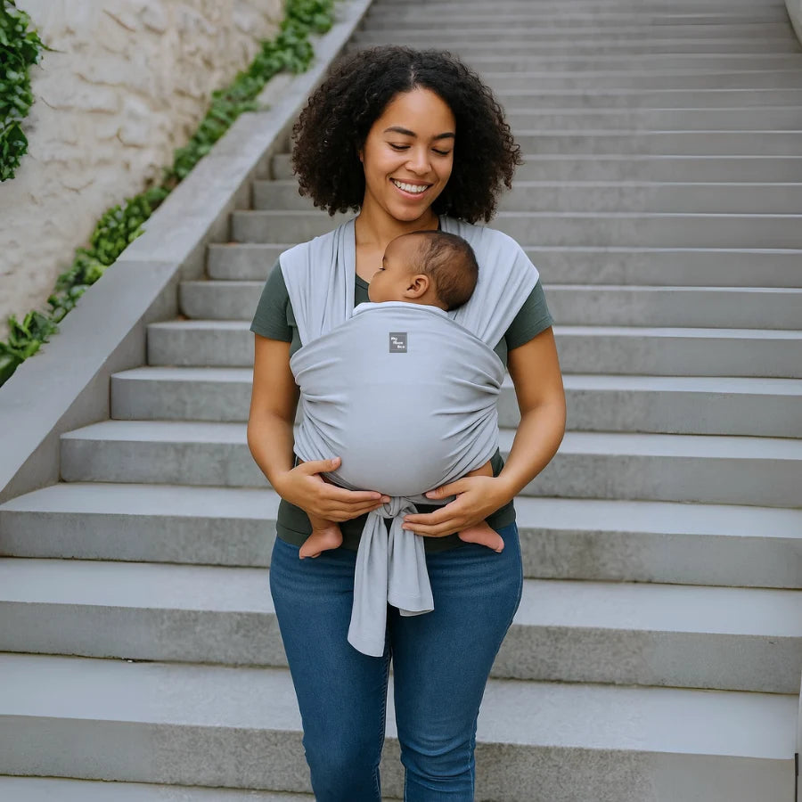 Une femme portant son bébé dans une Écharpe de portage Mymombox, gris lilas