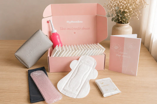 Coffret post-partum MyMomBox avec serviettes hygiéniques, douche périnéale, poche de froid, trousse et carnet post-partum.