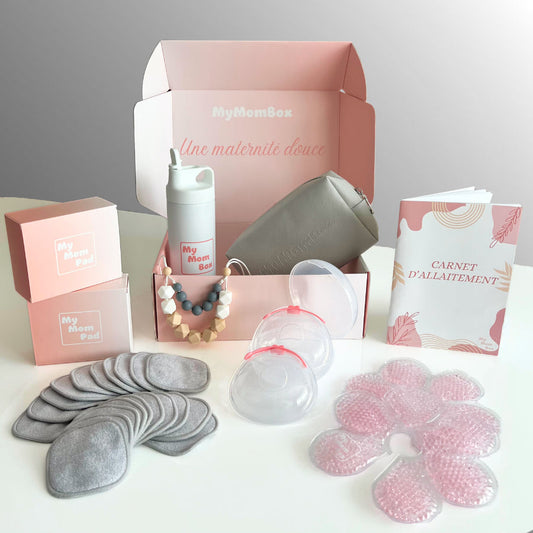 Box Allaitement MyMomBox ouverte dévoilant ses accessoires : gourde, trousse, carnet d’allaitement, coussinets lavables, colliers d'allaitement, recueils-lait et packs chaud-froid pour soulager l’allaitement.
