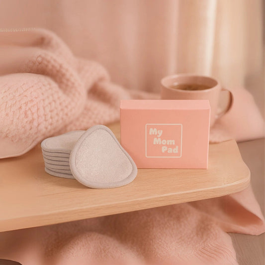 Coussinets d’allaitement lavables beiges avec boîte de rangement "My Mom Pad", posés sur une table en bois. Une solution douce et réutilisable pour l’allaitement.