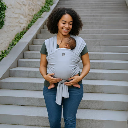 Une femme portant son bébé dans une Écharpe de portage Mymombox, gris lilas